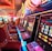 A brightly lit casino interior featuring a row of colorful slot machines. The neon lights create a vibrant atmosphere, with patterned carpeting adding to the decor. Stools are aligned neatly in front of each machine.