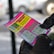 A person wearing black gloves is holding a colorful lottery scratch-off ticket. The ticket includes information about a $1,000,000 guaranteed minimum payout and features multiple games with various prize amounts.